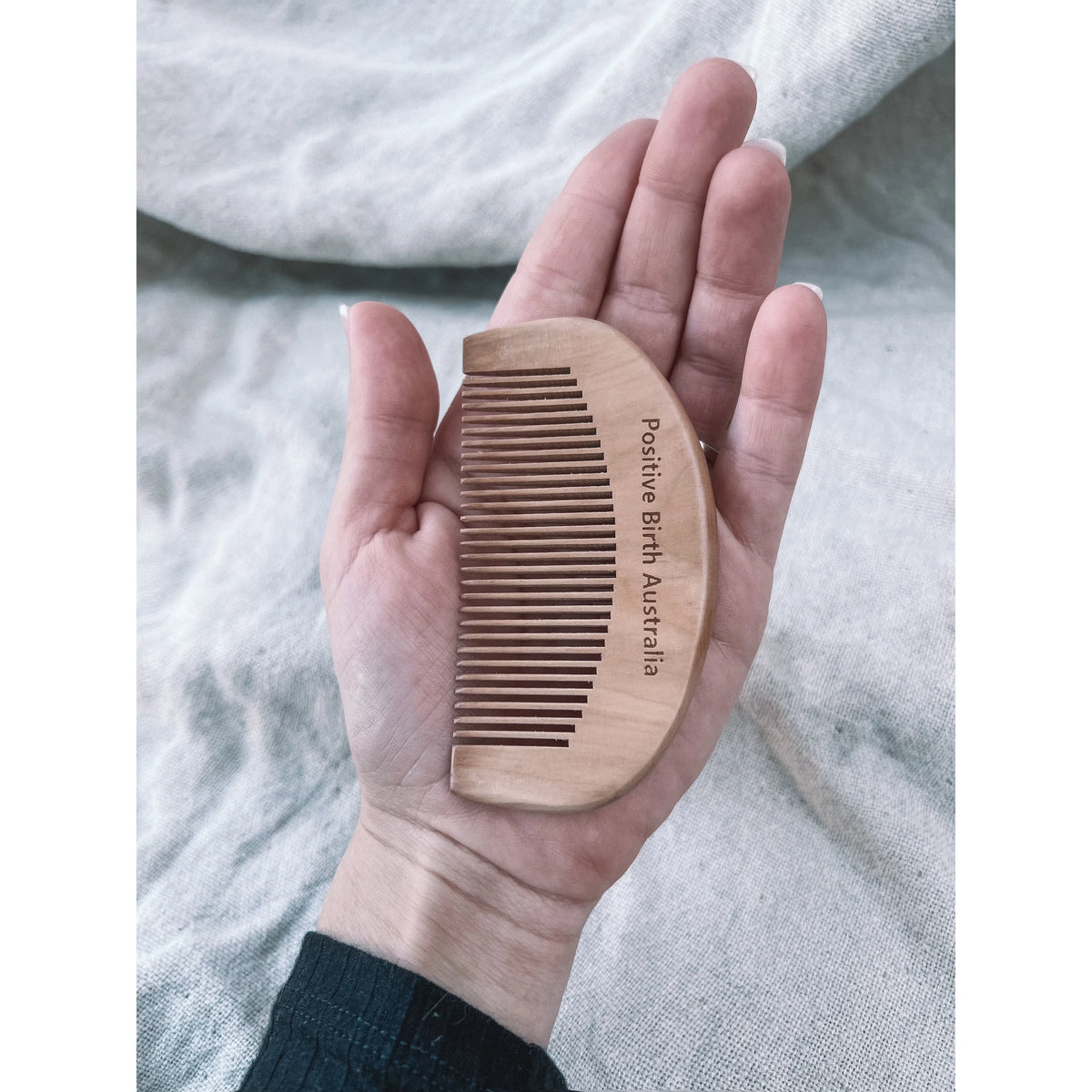 wooden birth comb in palm of hand